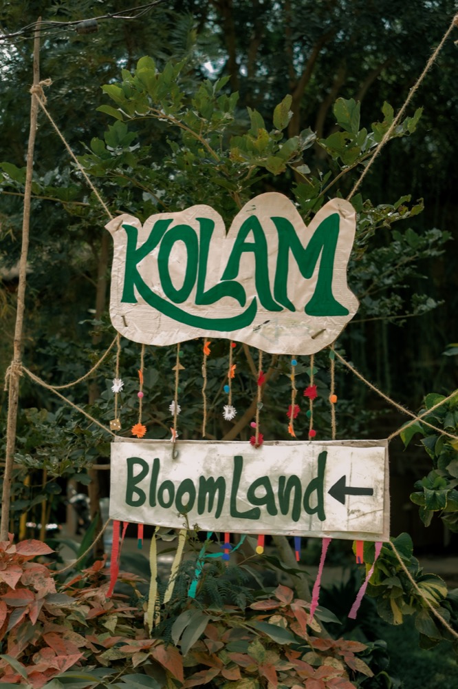 Hand-painted Kolam and BloomLand signage in the trees